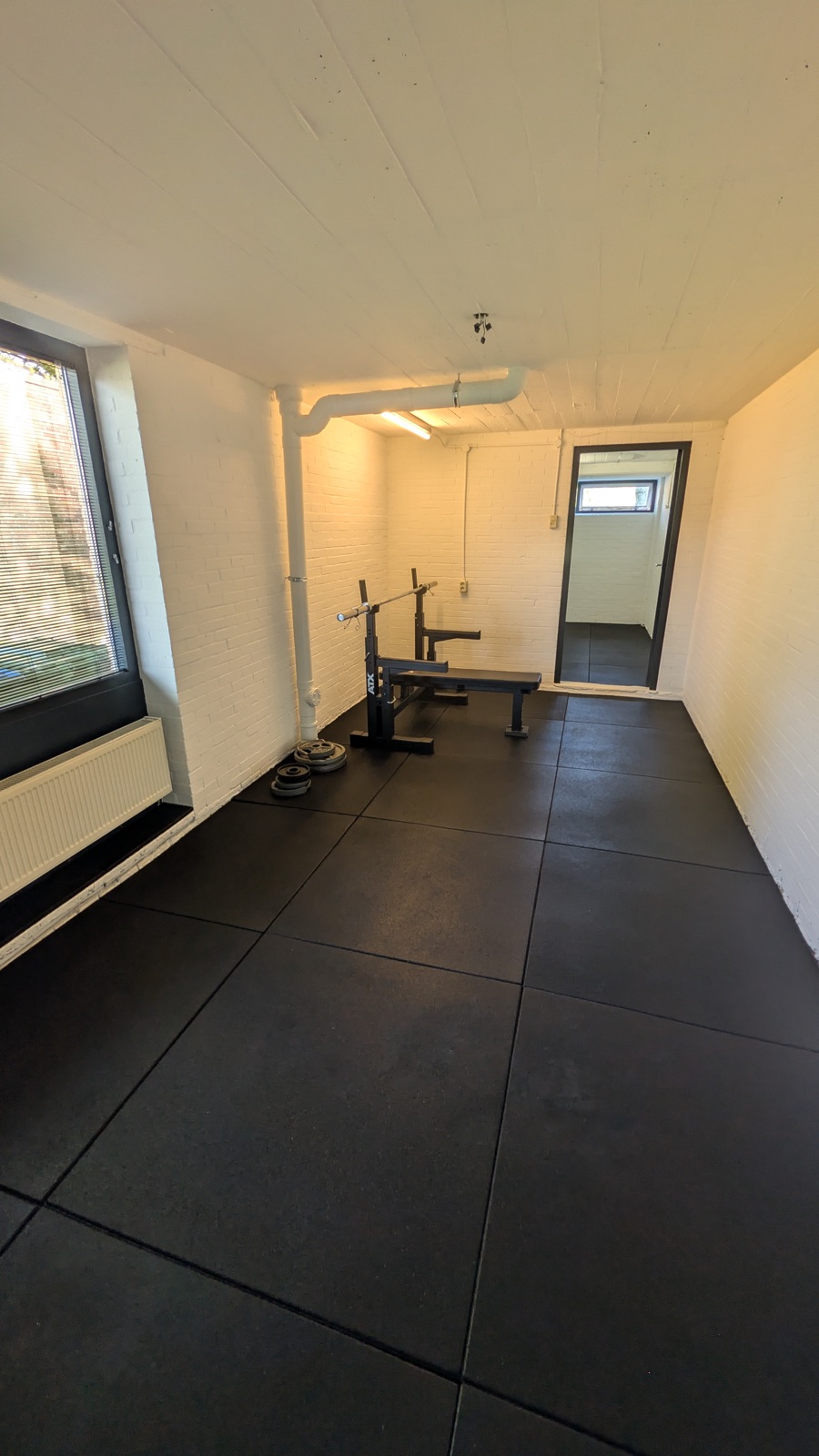 Wit gespoten wanden en plafond in een verbouwde fitnessruimte